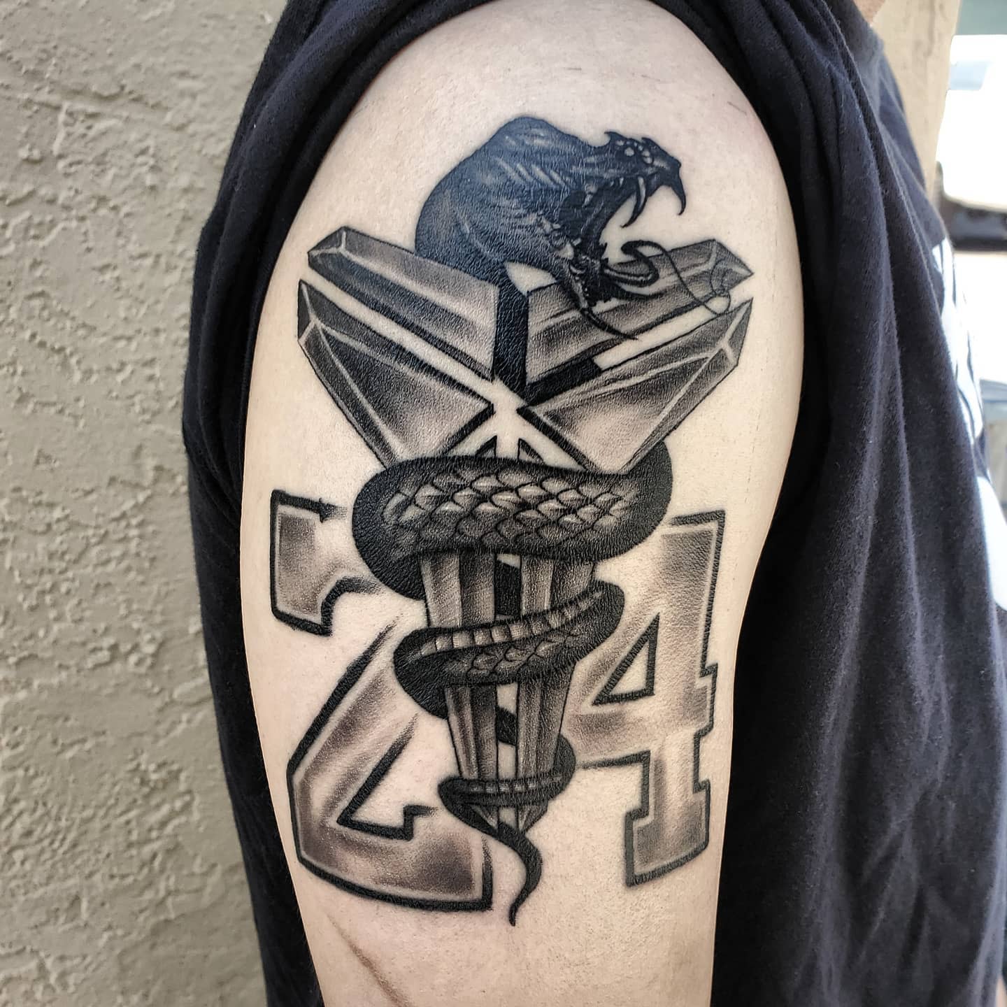 Tattoo of a snake forming the number 24 with a roaring bear on top on an upper arm - Black mamba Kobe Bryant tattoo